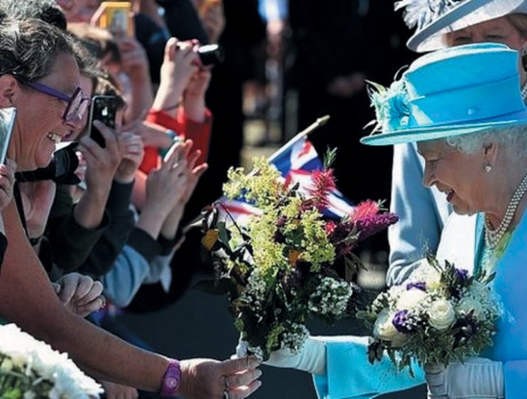 Queen Elizabeth II receives another bouquet from the crowd at Chatsworth in July 2014.