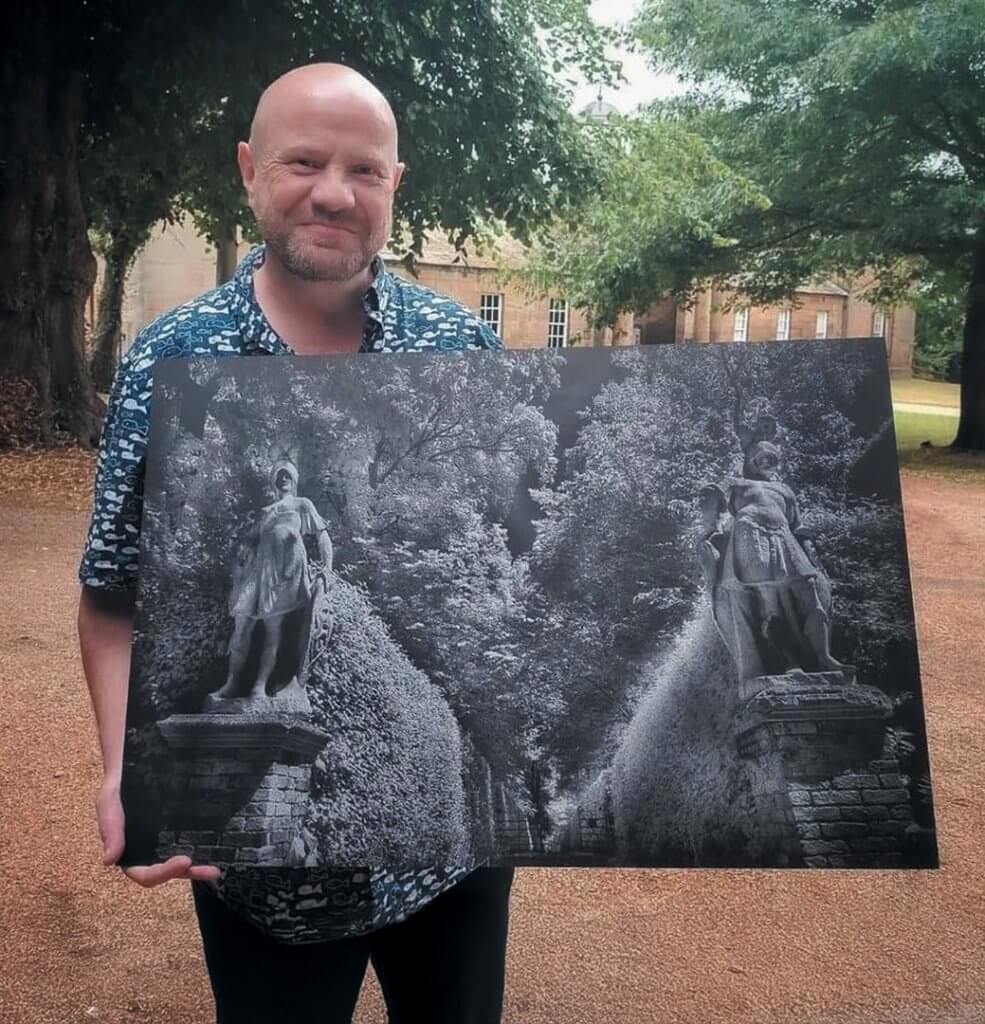 John Parker holding his photo of Renishaw Hall garden outside the hall.