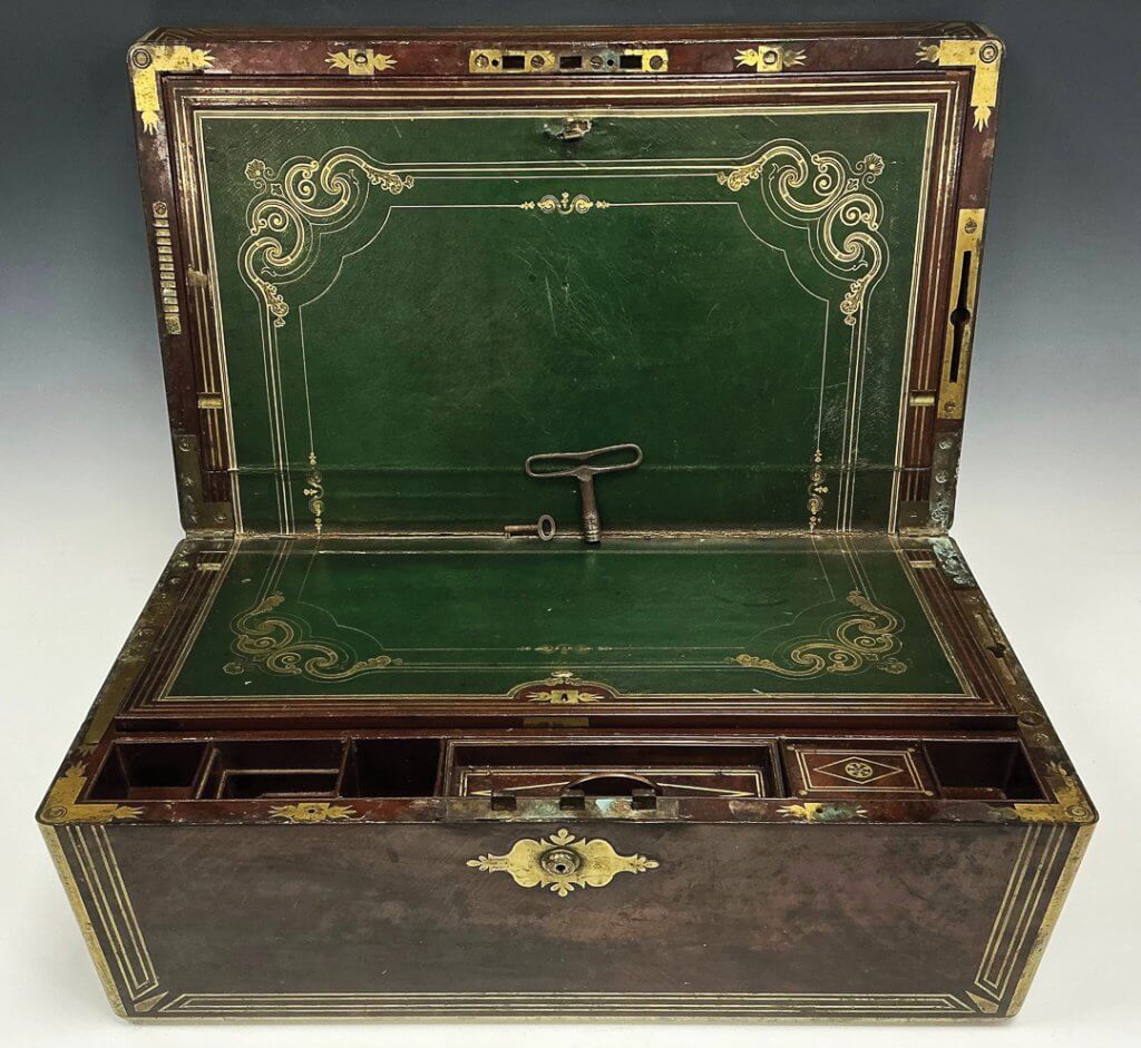 This 19th century brass-bound ship’s captain’s campaign writing box dates back to around 1840. An unusual feature of the box is the locking mechanism operated by the large key, allowing it to be attached to a tabletop and not move about in rough seas.