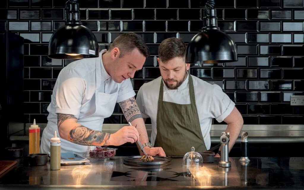 Executive chef Adam Harper (left) showing a chef how to prepare the dish.