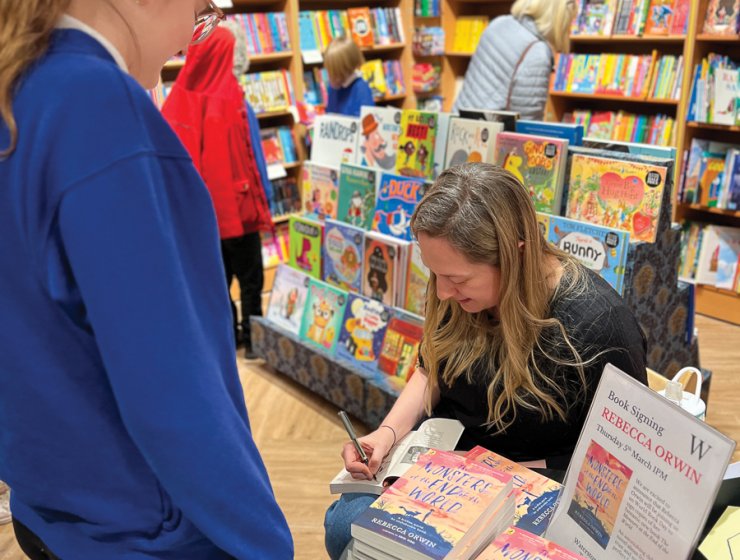 Becky signs a book to her old school, Holme Hall Primary