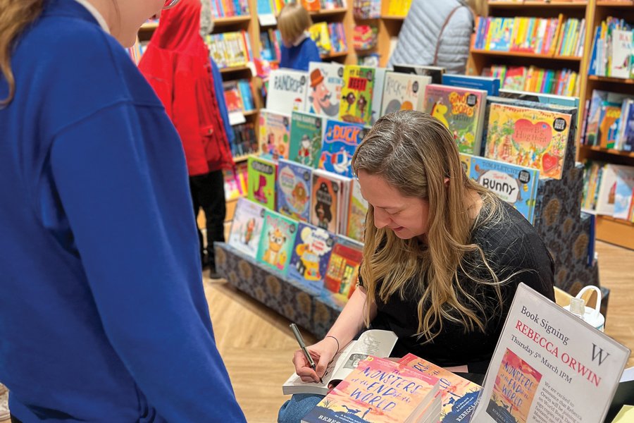Becky signs a book to her old school, Holme Hall Primary