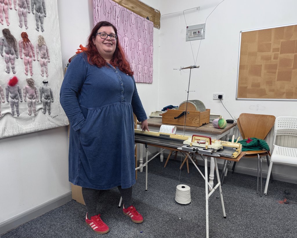 Sarah in her workshop with her mother’s trusty knitting machine. The artwork hanging on the walls are examples of her earlier work. Picture: Marian Scaife