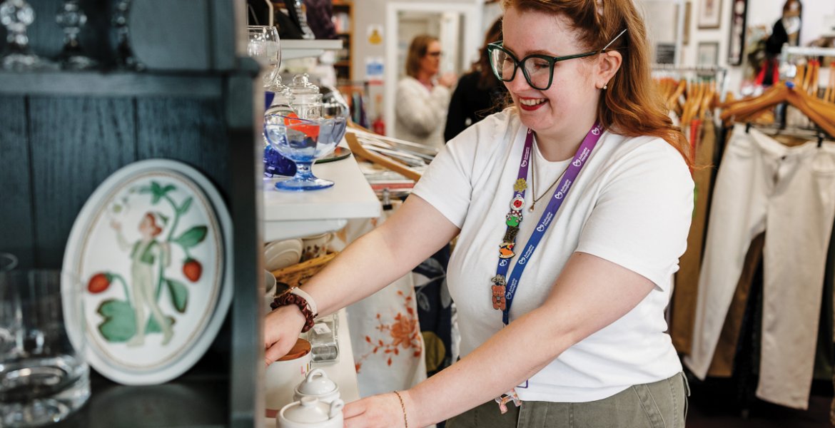 A volunteer arranges homewares to tempt shoppers