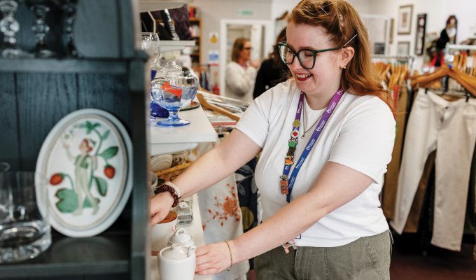 A volunteer arranges homewares to tempt shoppers
