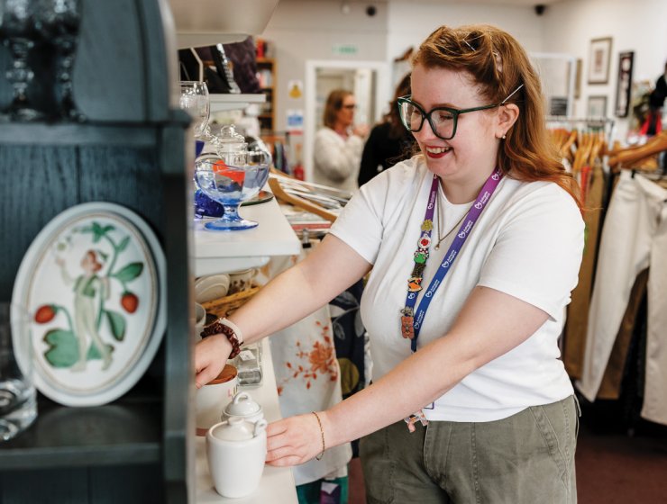 A volunteer arranges homewares to tempt shoppers